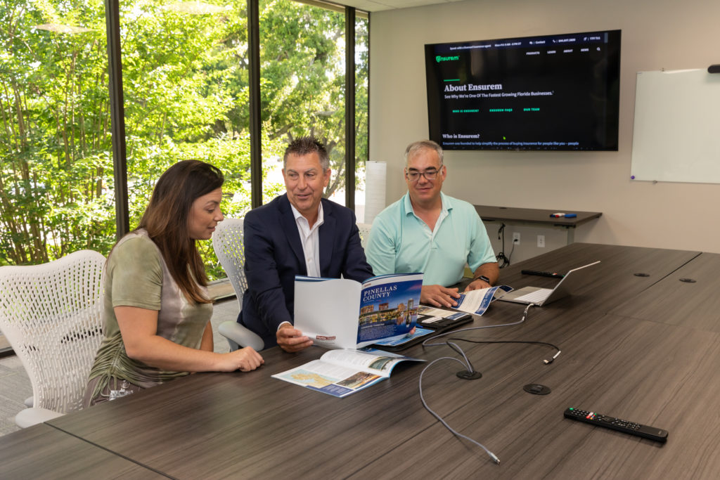 Image of three people meeting at a table reviewing a magazine about Pinellas County.