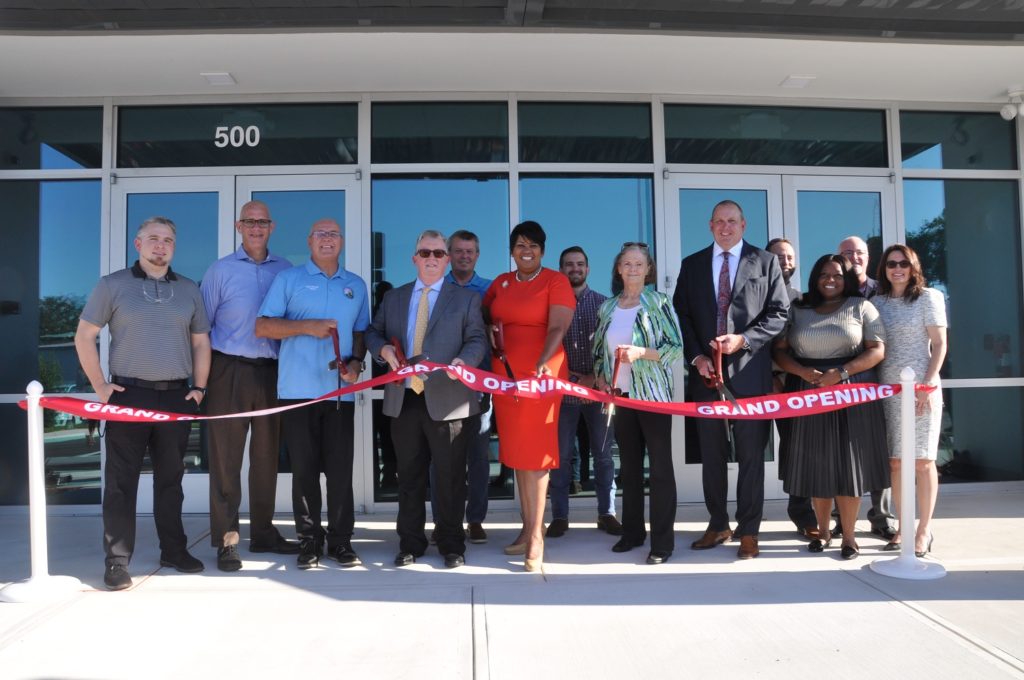 Image of PCED and business staff cutting a ribbon in front of an industrial building.