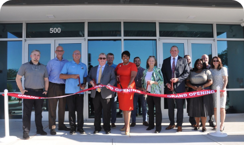 Image of businesses standing in front of a building cutting a ribbon for a ceremony.
