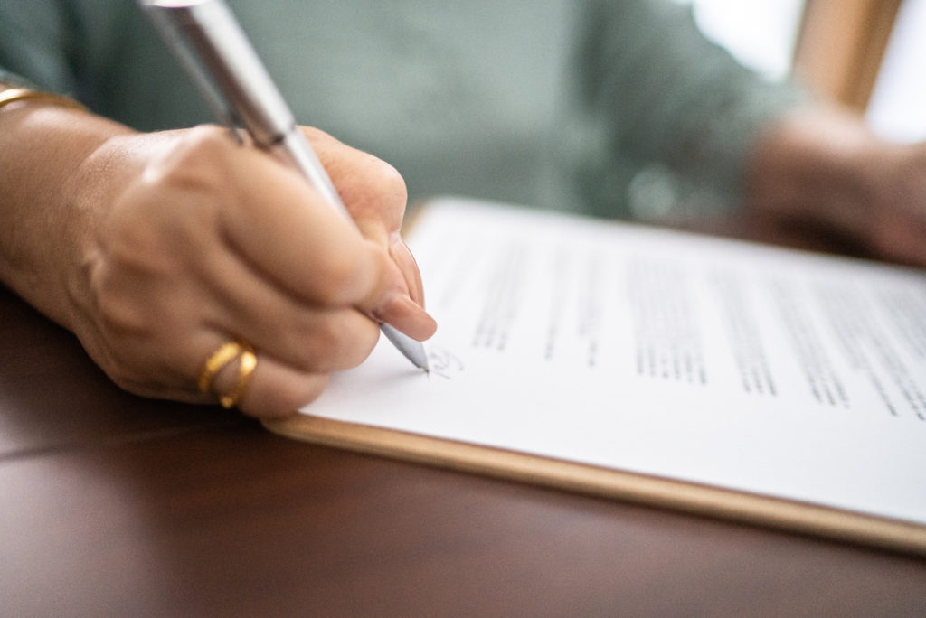 Image of Close up of document being signed by woman. 