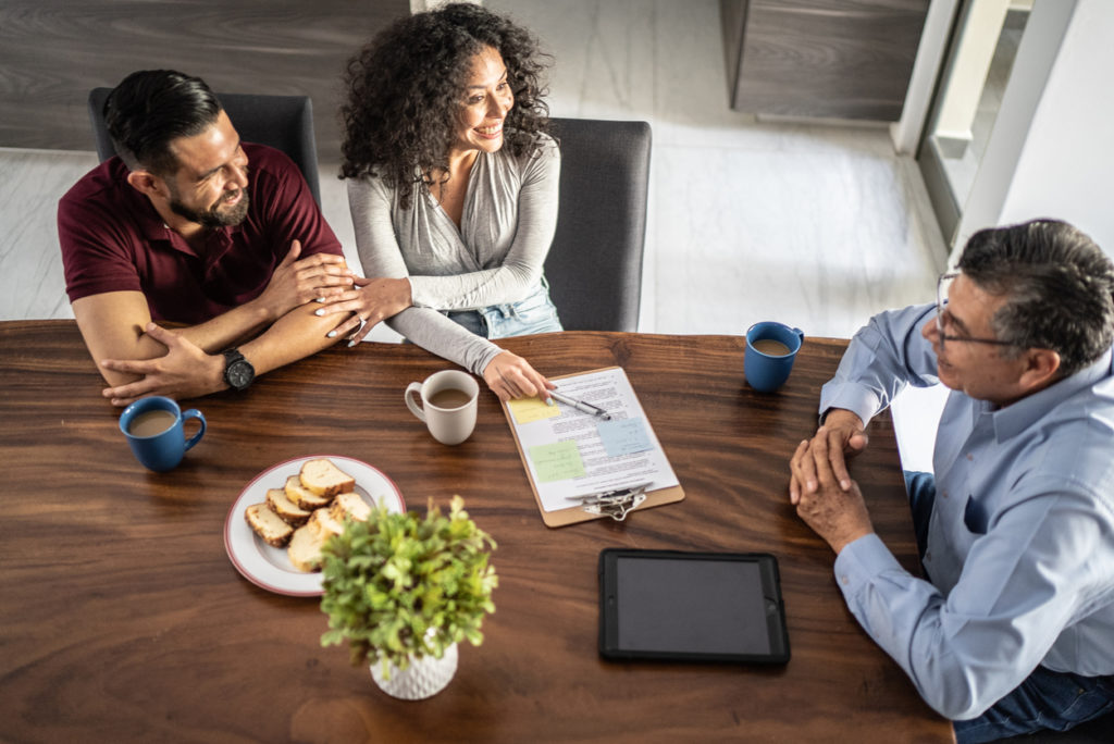 Mid adult couple having a meeting with real estate agent (or financial advisor) at house.