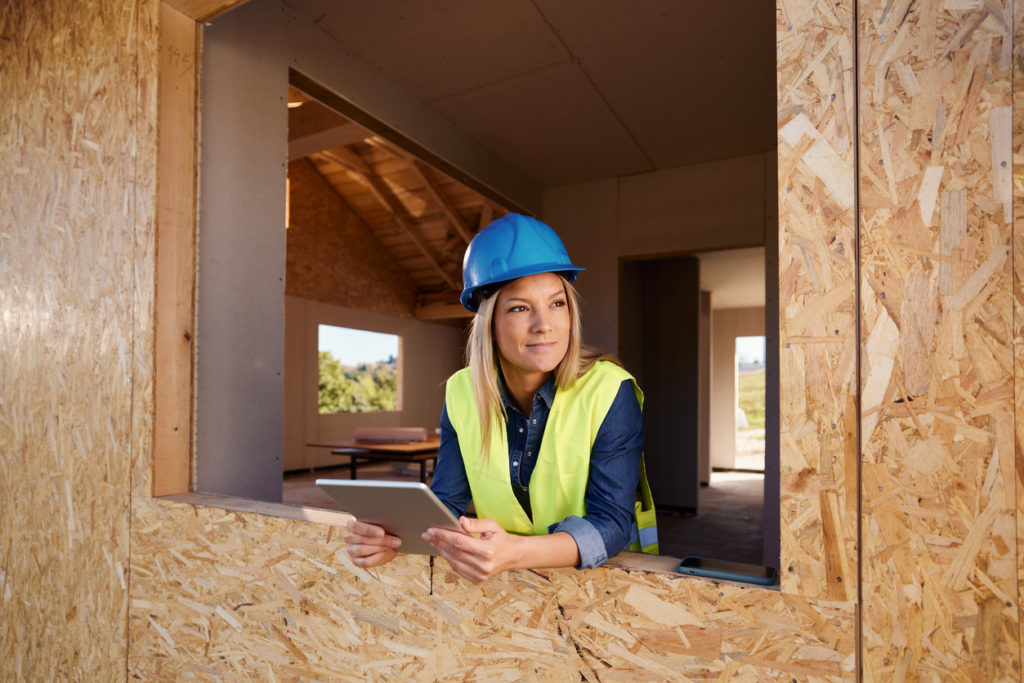 Female real estate developer using touchpad at construction site.